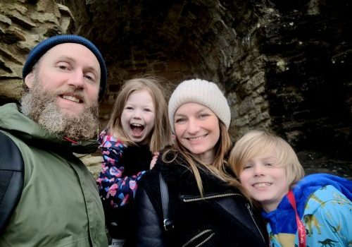 Mum, dad and small son and little girl taking a family selfie while out on a walk
