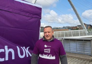 John at the Newcastle Bridges Walk, wearing his purple Kidney Research UK tshirt with the river and bridge behind him.