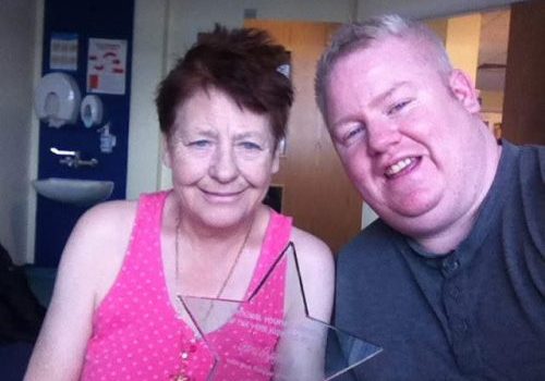Mum and son who are holding a star trophy