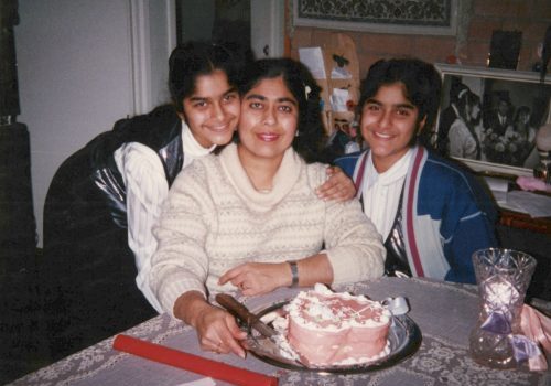 Mum with her two daughters celebrating a birthday round a table with a cake