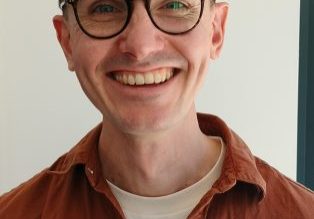 Man wearing black glasses and a brown shirt.
