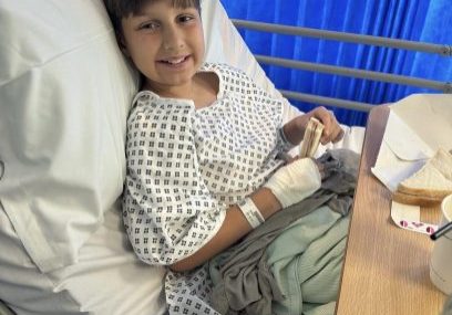 Ellis, in hospital bed, holding a sandwich